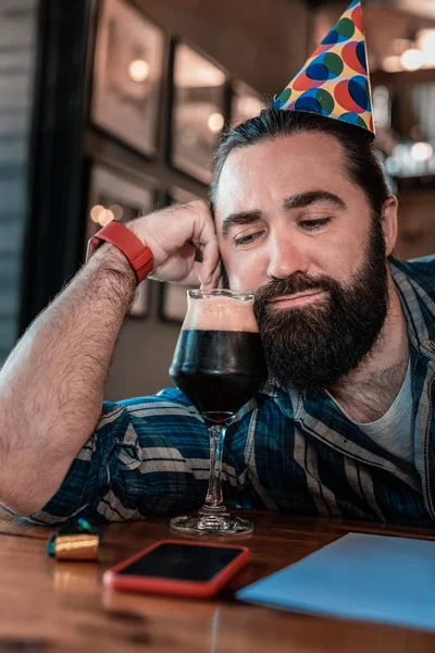 Brodaty mężczyzna ogląda szkła z ciemne piwo — Zdjęcie stockowe