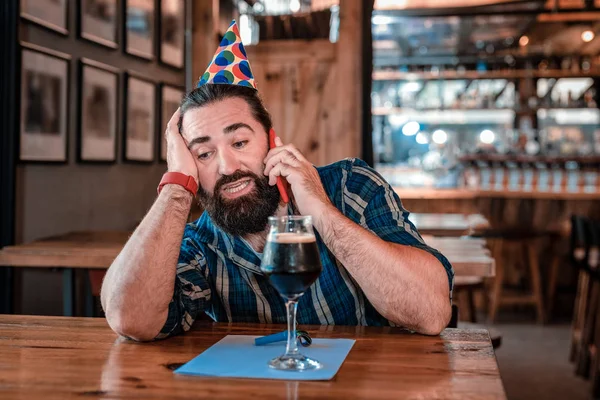Мужчина звонит своим друзьям и ждет их в пабе в свой день рождения — стоковое фото