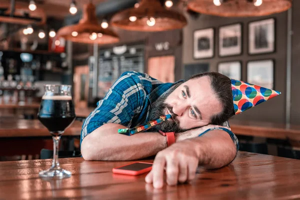 Mature man wearing birthday hat blowing into penny whistle