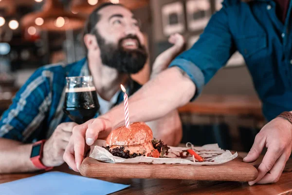 Agradable camarero brining buena hamburguesa de carne con vela de cumpleaños poco — Foto de Stock