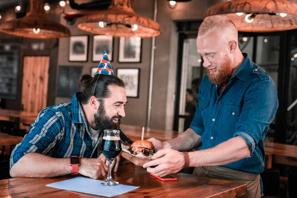 Feliz cumpleaños hombre soplando vela en hamburguesa de carne en el pub —  Fotos de Stock