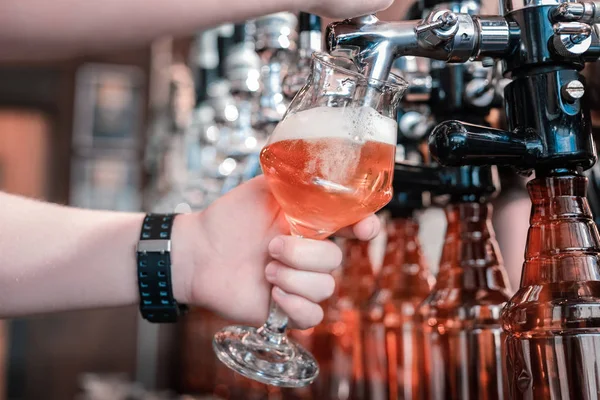 Barman segurando vidro enquanto o enche com cerveja escura artesanal — Fotografia de Stock