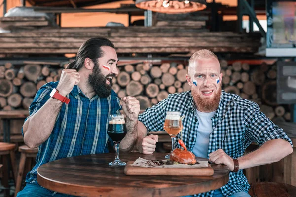 Un ami brun se joint à son ami au pub pour regarder le match. — Photo