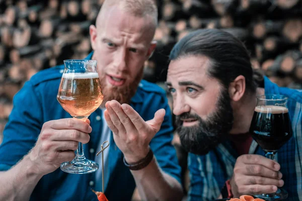Dos hombres barbudos mirando el nuevo tipo de cerveza artesanal ligera — Foto de Stock