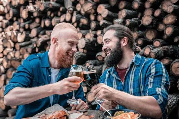 Dwóch brodatych mężczyzn uśmiechający się brzęk ich szklanki piwa — Zdjęcie stockowe