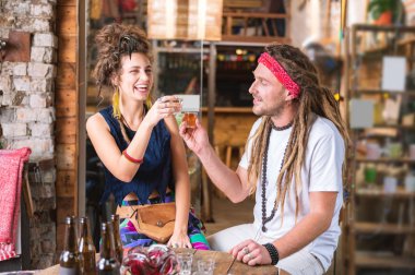 Laughing couple of hippies drinking tequila celebrating anniversary clipart