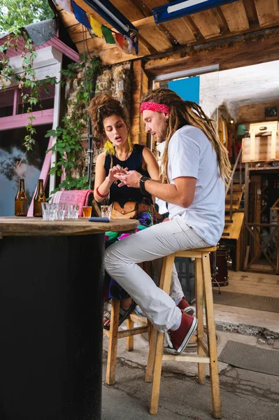 Hippie muž s dlouhými vlasy ukazovat fotky na svém telefonu — Stock fotografie