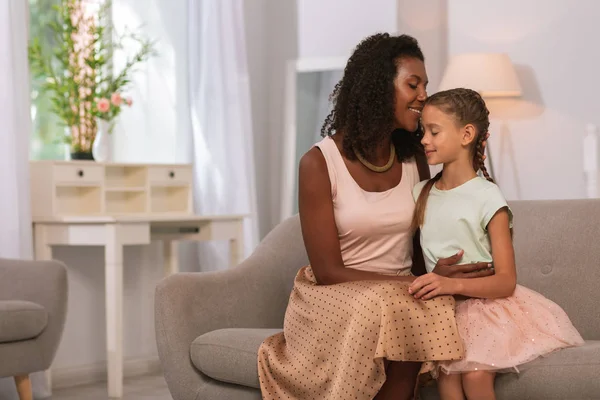 Mujer positiva encantada sentada junto con su hija —  Fotos de Stock