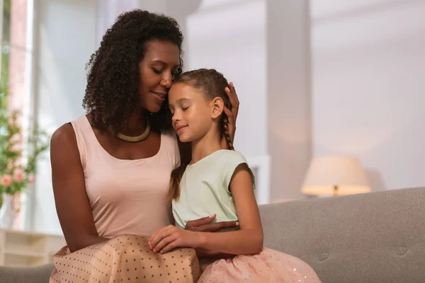 Agradable mujer agradable abrazando a su hija en casa —  Fotos de Stock