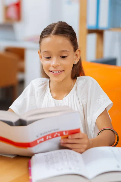 Menina de espírito alto lendo um livro em um quarto — Fotografia de Stock