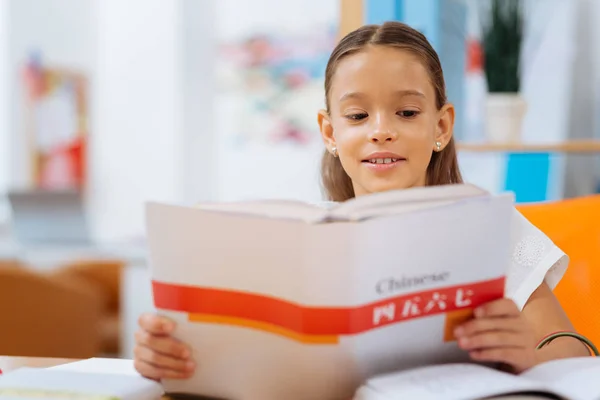 Серйозна школярка читає книгу дуже уважно — стокове фото