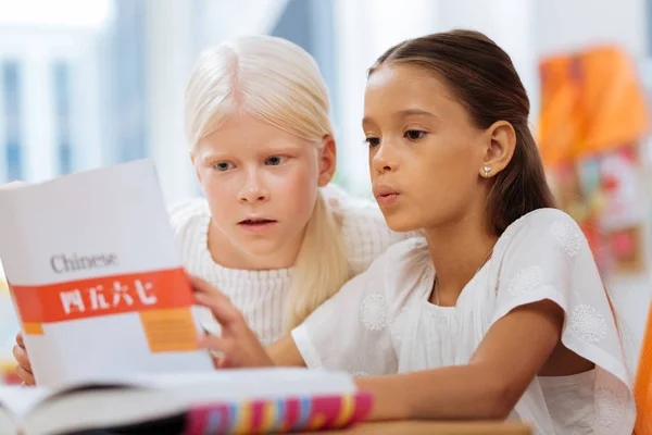 Amigos sérios da escola lendo um livro juntos — Fotografia de Stock