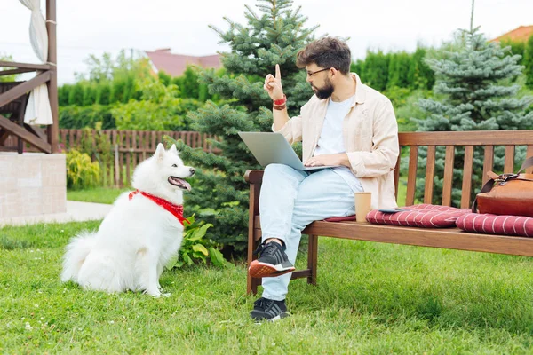 Redactor independiente calmando a su perro mientras trabaja fuera — Foto de Stock