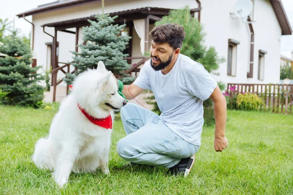 Moderner Mann teilt seinen Kopfhörer mit niedlichen weißen Husky — Stockfoto