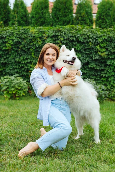 Donna allegra sorridente mentre incontra il suo cane bianco — Foto Stock