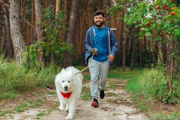 Dark-haired businessman running with his dog in the morning