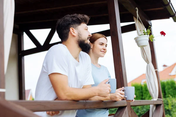 Femme et mari debout sur leur balcon en train de boire du café — Photo