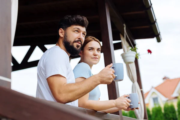 Mladý pár hospodářství modré šálky s kávou stojí na balkóně — Stock fotografie