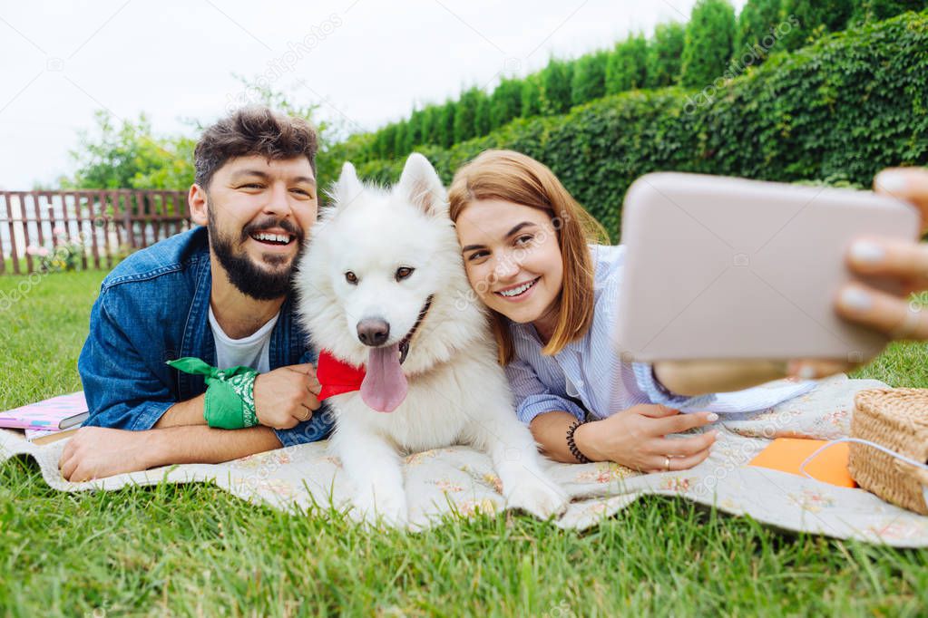 Blonde-haired woman making selfie with her husband and dog