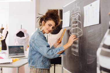 Kroki ayrıntıları eklerken gülümseyen pozitif terzi