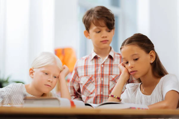 Уставшие дети читают скучную книгу — стоковое фото