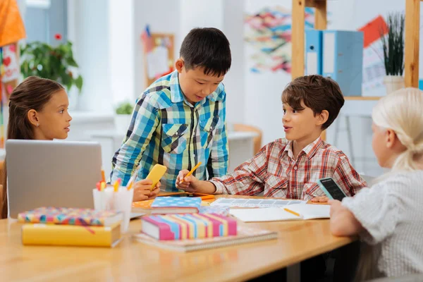 Crianças interessadas discutindo questões escolares juntas em uma sala de aula — Fotografia de Stock