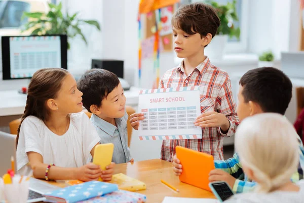 Netter Junge zeigt den Kumpels einen Tisch — Stockfoto