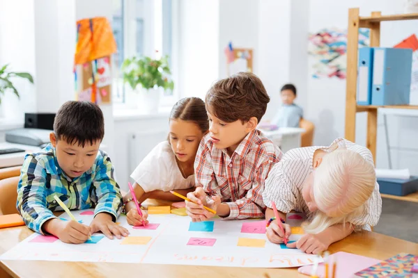 Schattige kinderen tekenen van een nieuwe poster in een klaslokaal — Stockfoto