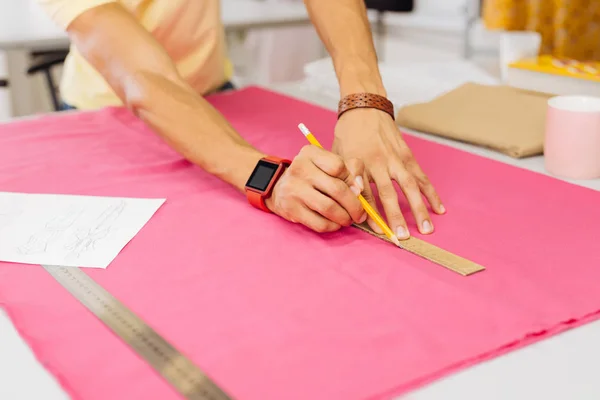 Close up van handen met liniaal en potlood op de textiel — Stockfoto