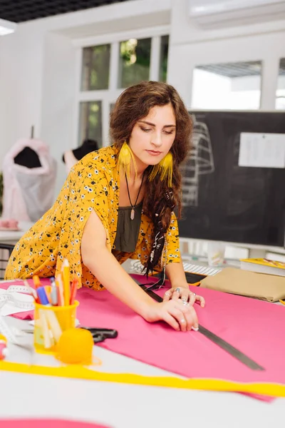 Costureira profissional olhando concentrado ao desenhar linhas em têxteis — Fotografia de Stock