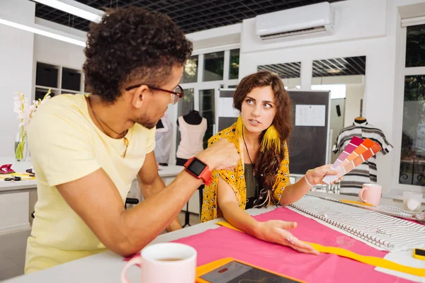 Thoughtful dressmakers discussing color palettes while being at work