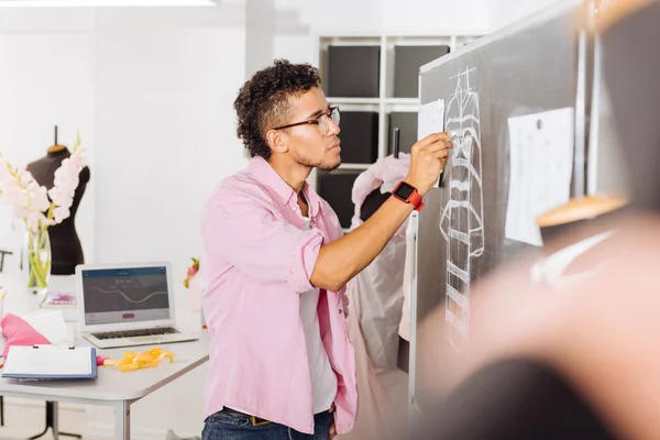 Calm designer drawing on the blackboard while working in atelier — Stock Photo, Image