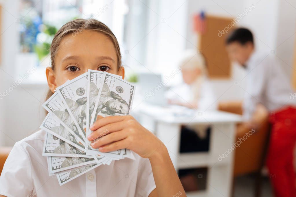 Cute small girl holding money in a hand