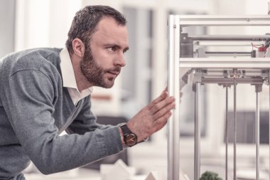 Sakallı konsantre yetişkin adam izliyor 3D printerlere harcama maddeler
