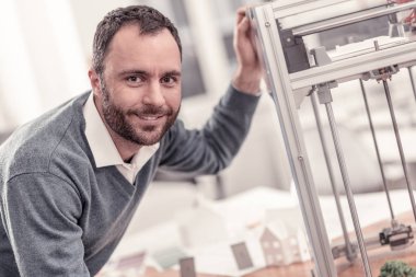 Smiling man printing something on 3D printer clipart