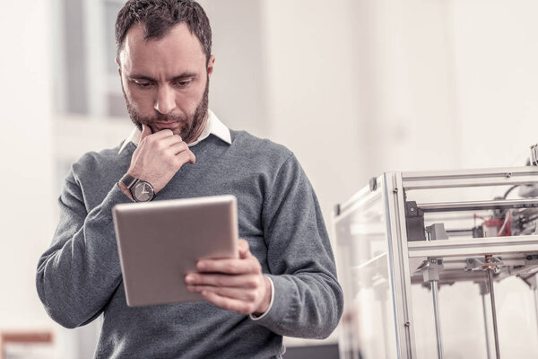 Concentrated adult man watching at his tablet