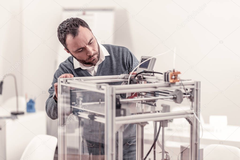 Bearded adult man working with 3D printer