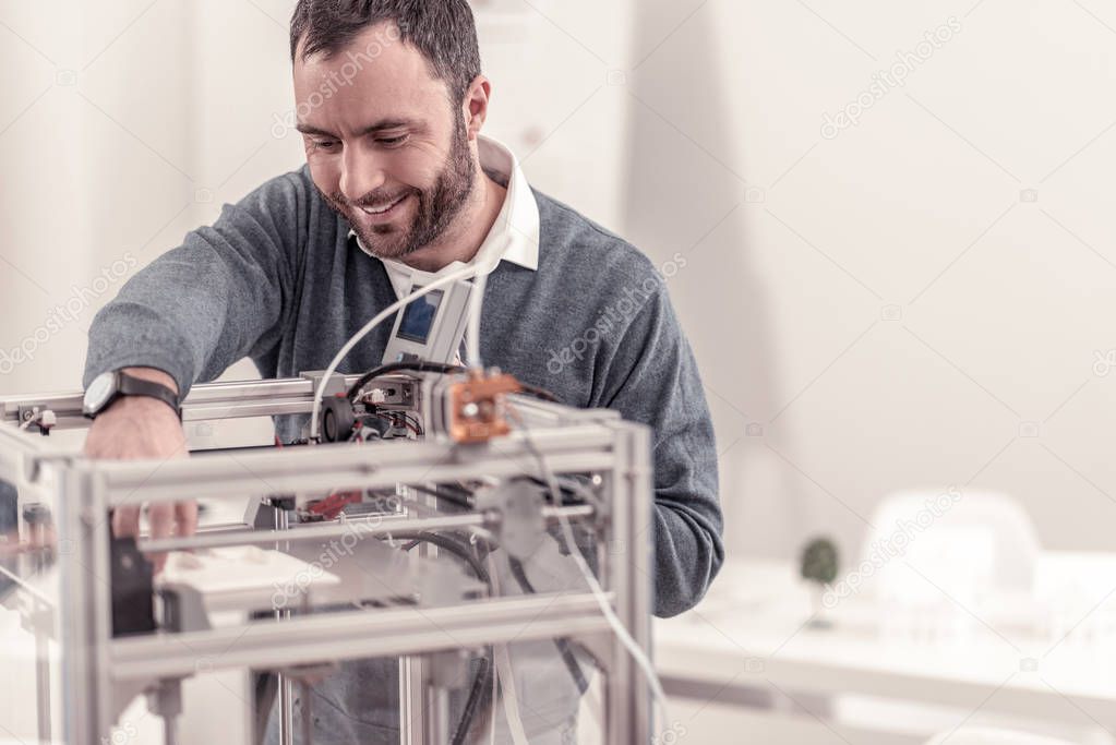 Smiling adult man testing new a3D printer