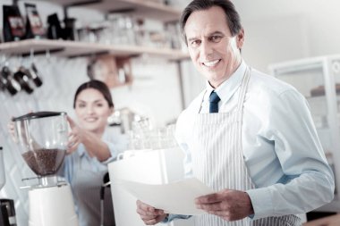 Belgeleri holding ve bir barista ayakta neşeli kafe sahibi