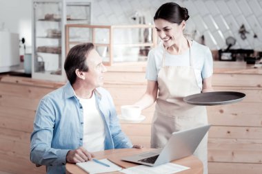 Bir tepsi tutarak ve kahve bir ziyaretçiye veren güzel garson