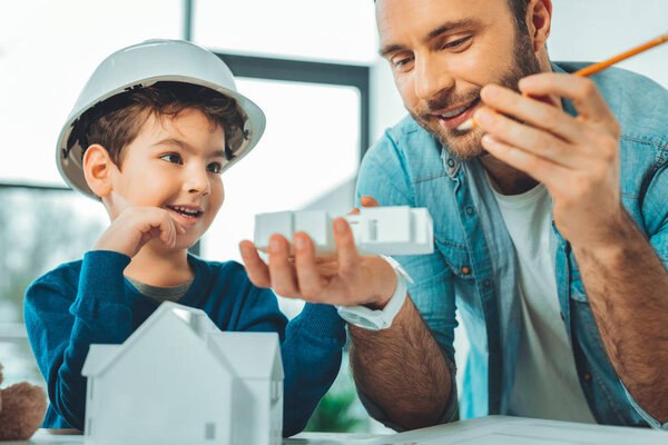 Удовлетворенный молодой мужчина смотрит на модель дома
