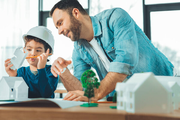 Concentrated boy playing with paper building