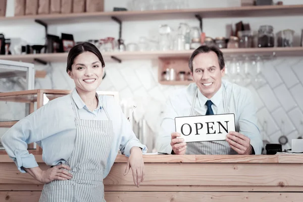 Friendly workers of the cafe leaning on the bar counter and smiling — Stock Photo, Image