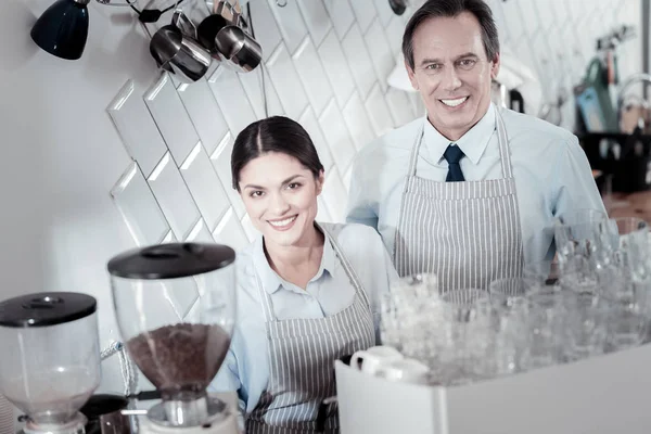 Baristas positifs souriant et debout près de la machine à café — Photo
