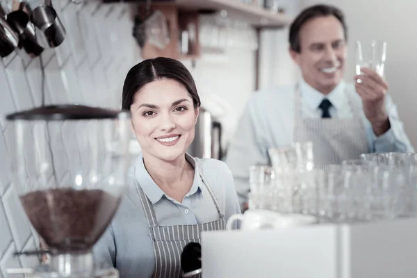 Destul de chelneriță zâmbind în timp ce stătea lângă aparatul de cafea — Fotografie, imagine de stoc