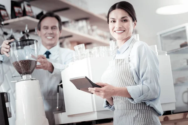 Handsome barista touching a coffee machine and a waitress smiling — Stock Photo, Image