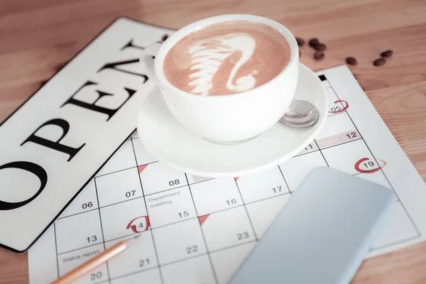 Foto lacônica de uma xícara de café e um sinal aberto em um calendário — Fotografia de Stock