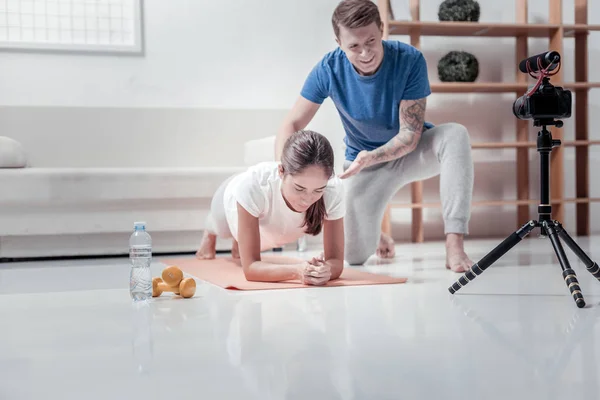 Bonito treinador mostrando exercícios com seu assistente — Fotografia de Stock