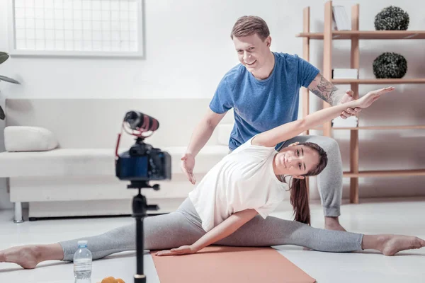 Hombre sonriente ayudando a la mujer haciendo ejercicios —  Fotos de Stock