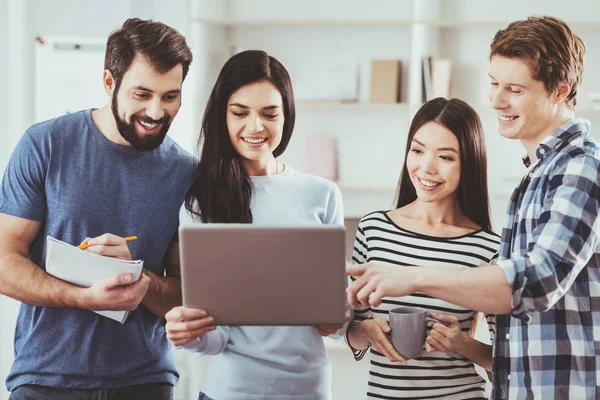 Vrolijke jonge mensen staan over de laptop — Stockfoto